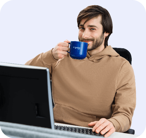 Ignitis darbuotojas geria kavą prie kompiuterio